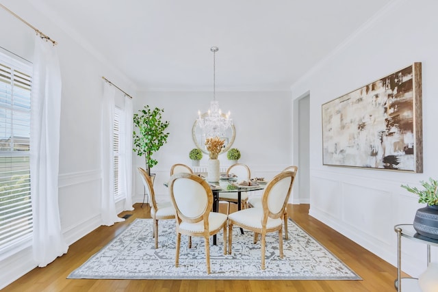 dining area featuring ornamental molding, wood-type flooring, and a notable chandelier