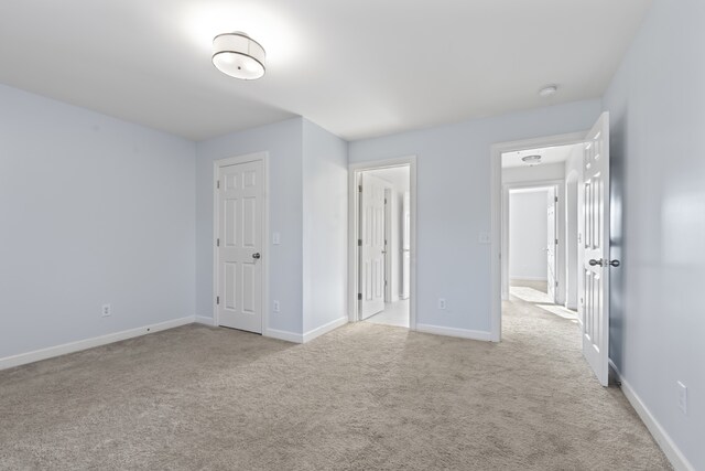 unfurnished bedroom with light colored carpet and a closet