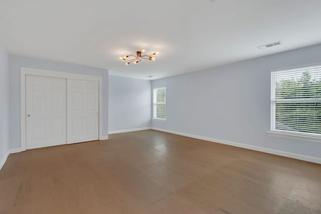 unfurnished bedroom with hardwood / wood-style flooring, a chandelier, and a closet