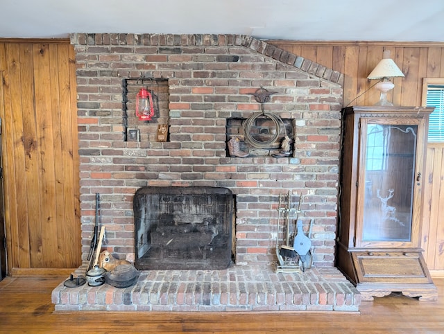 interior details with a fireplace, wood-type flooring, and wooden walls