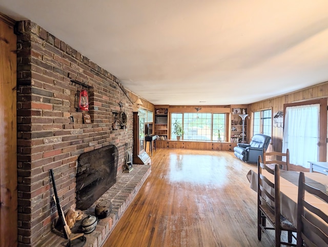 unfurnished living room with a fireplace, wooden walls, and wood-type flooring