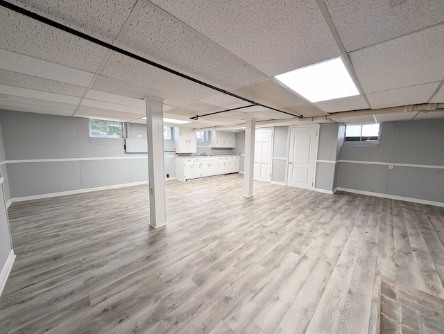 basement with light hardwood / wood-style floors, a drop ceiling, and sink