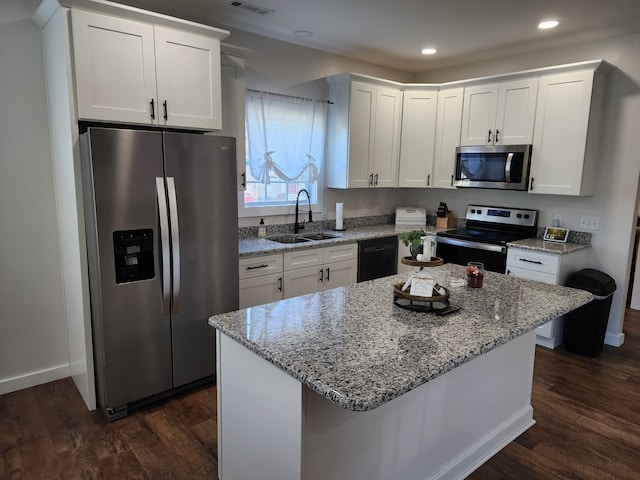 kitchen featuring dark hardwood / wood-style flooring, white cabinets, stainless steel appliances, and a kitchen island