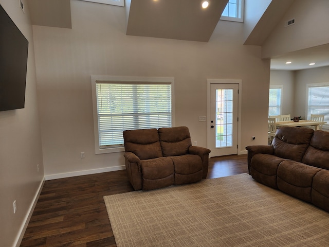 living room featuring a towering ceiling, dark hardwood / wood-style floors, and plenty of natural light