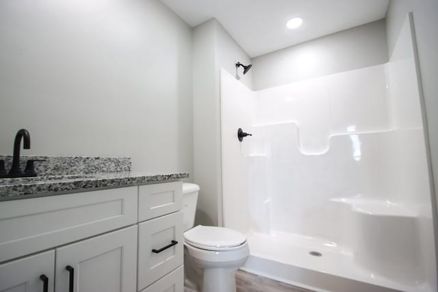 bathroom with wood-type flooring, vanity, toilet, and walk in shower