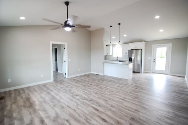 unfurnished living room featuring ceiling fan, light hardwood / wood-style flooring, vaulted ceiling, and sink