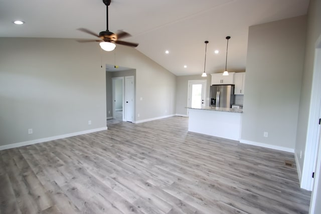 unfurnished living room featuring light wood-type flooring, vaulted ceiling, and ceiling fan