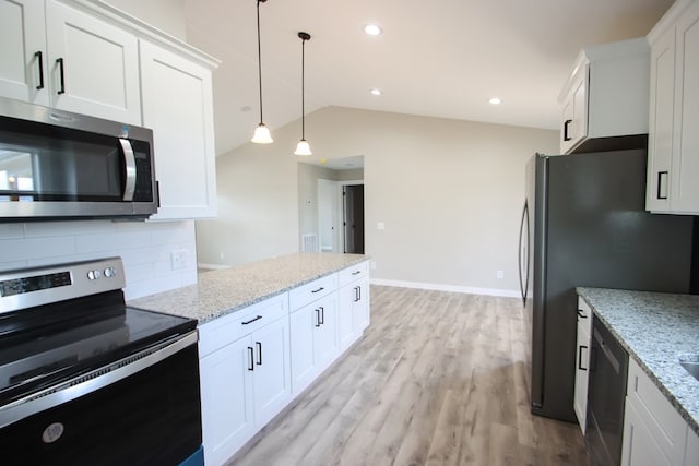 kitchen with light stone countertops, stainless steel appliances, white cabinetry, and lofted ceiling