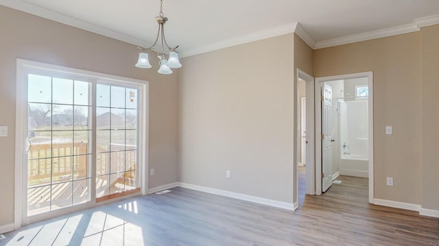 unfurnished dining area with hardwood / wood-style floors, crown molding, and an inviting chandelier