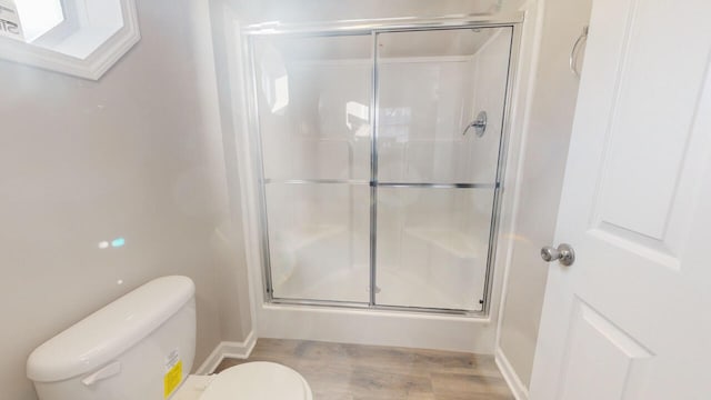 bathroom with an enclosed shower, toilet, and hardwood / wood-style flooring