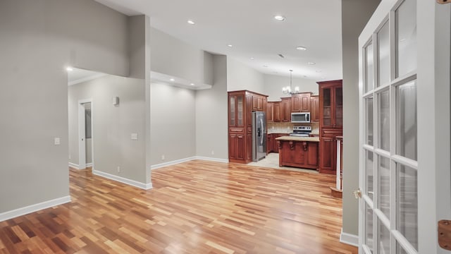 kitchen with light hardwood / wood-style flooring, a kitchen island, pendant lighting, and appliances with stainless steel finishes