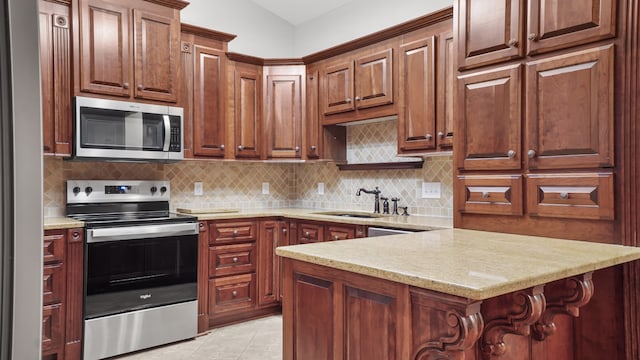 kitchen featuring a kitchen breakfast bar, sink, tasteful backsplash, light tile patterned flooring, and stainless steel appliances