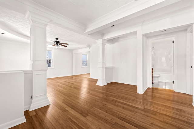 unfurnished living room featuring ornate columns, ornamental molding, a textured ceiling, ceiling fan, and hardwood / wood-style flooring