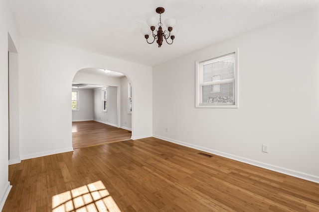 unfurnished room with a notable chandelier and hardwood / wood-style flooring