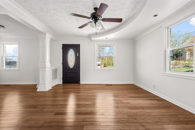 foyer entrance featuring decorative columns, a textured ceiling, ceiling fan, crown molding, and dark wood-type flooring