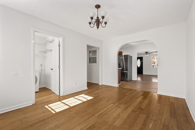 interior space featuring wood-type flooring, ceiling fan with notable chandelier, and washer / dryer