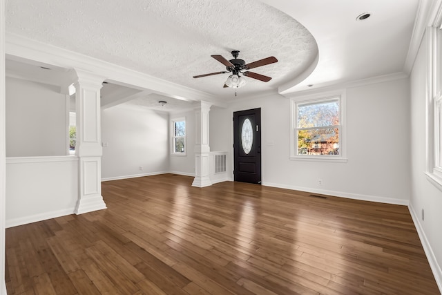 entrance foyer featuring ornate columns, a textured ceiling, ceiling fan, dark wood-type flooring, and crown molding