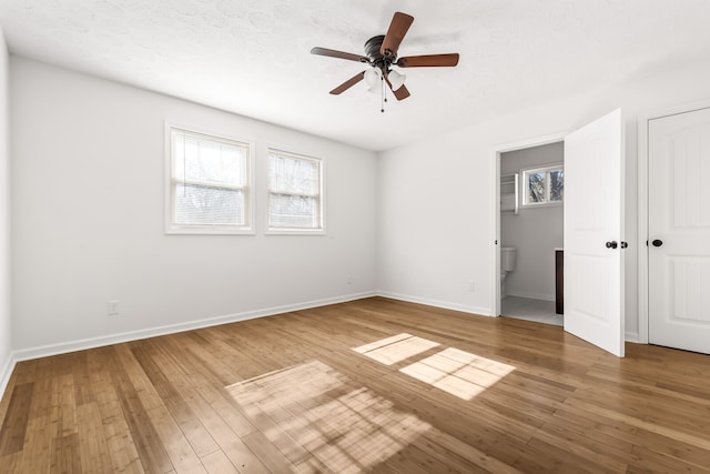 unfurnished bedroom with wood-type flooring, a textured ceiling, multiple windows, and ceiling fan