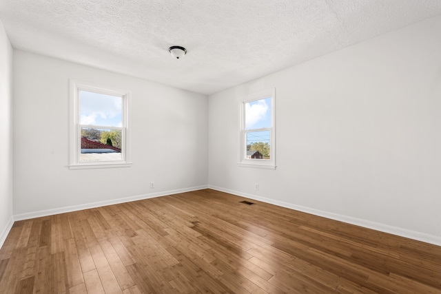 spare room with a wealth of natural light, hardwood / wood-style flooring, and a textured ceiling