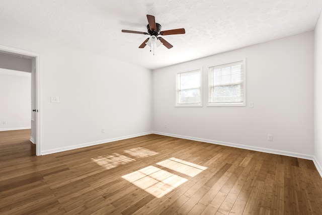 unfurnished room with ceiling fan, dark wood-type flooring, and a textured ceiling