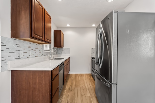 kitchen with decorative backsplash, sink, appliances with stainless steel finishes, and light hardwood / wood-style floors