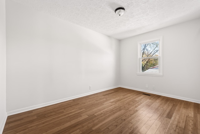 empty room featuring wood-type flooring and a textured ceiling