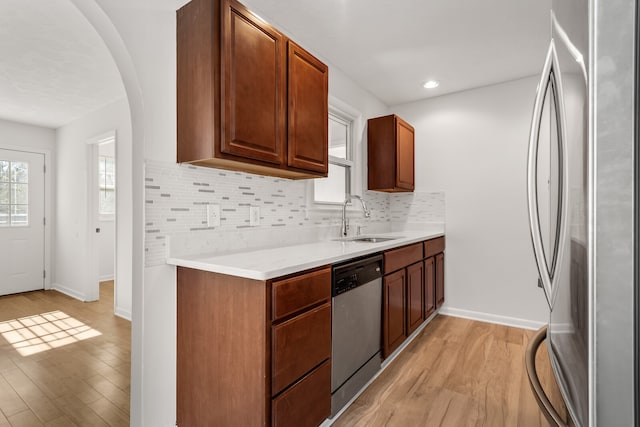 kitchen featuring sink, appliances with stainless steel finishes, light wood-type flooring, and tasteful backsplash