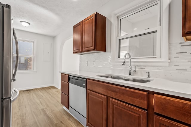 kitchen featuring appliances with stainless steel finishes, a textured ceiling, tasteful backsplash, and sink