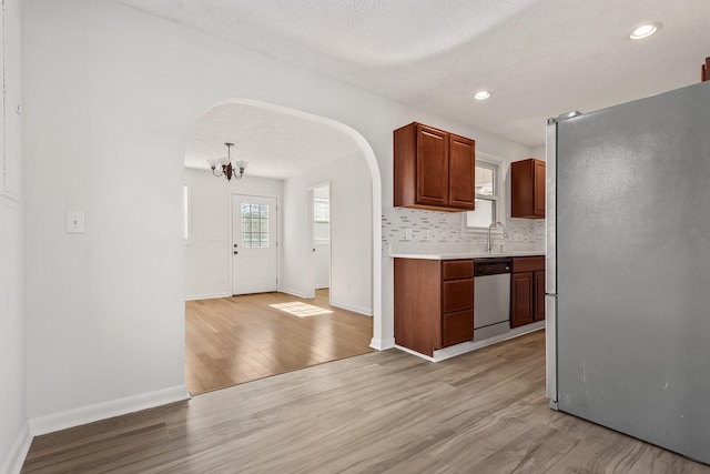 kitchen with hanging light fixtures, a chandelier, light hardwood / wood-style floors, a textured ceiling, and appliances with stainless steel finishes