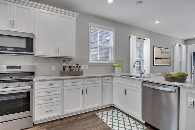 kitchen featuring white cabinetry, sink, dark hardwood / wood-style flooring, stainless steel appliances, and light stone counters