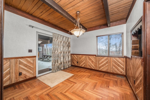 spare room with beam ceiling, a wealth of natural light, and wood ceiling