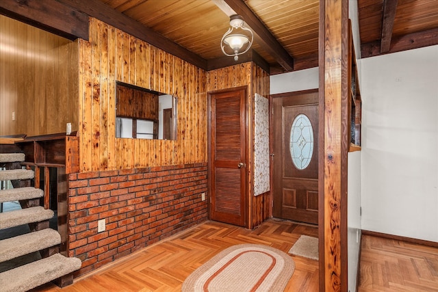 foyer featuring brick wall, wooden walls, beamed ceiling, wooden ceiling, and light parquet flooring