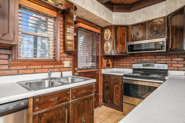 kitchen featuring light tile patterned floors, sink, appliances with stainless steel finishes, and dark brown cabinets