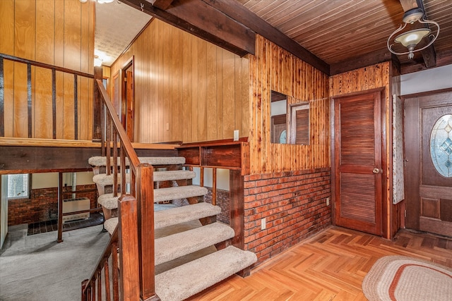 entrance foyer featuring brick wall, wood walls, beamed ceiling, light parquet floors, and wood ceiling