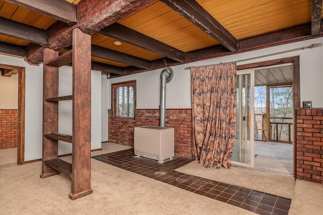 interior space with a wood stove, wooden ceiling, brick wall, and dark carpet