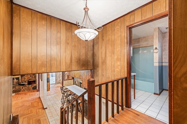 hall with light tile patterned floors, a textured ceiling, and wooden walls