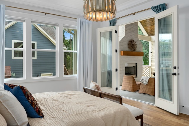 bedroom with crown molding, a chandelier, a fireplace, and light hardwood / wood-style floors