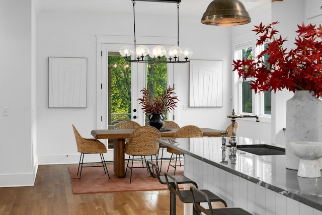 dining room featuring hardwood / wood-style floors, sink, a healthy amount of sunlight, and an inviting chandelier