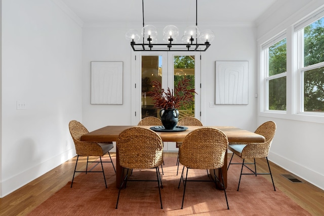 dining room featuring an inviting chandelier, ornamental molding, and hardwood / wood-style flooring