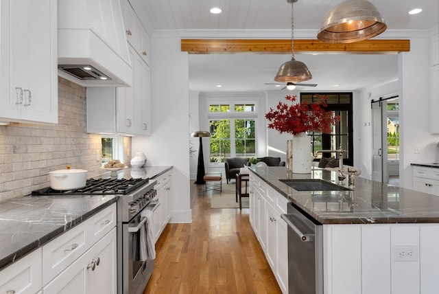 kitchen featuring a barn door, a center island, light hardwood / wood-style floors, decorative light fixtures, and stainless steel appliances