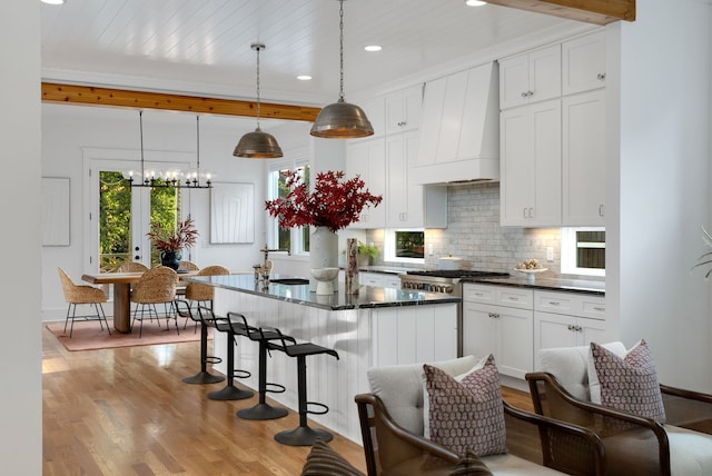 kitchen with custom range hood, decorative light fixtures, light hardwood / wood-style flooring, a chandelier, and white cabinetry