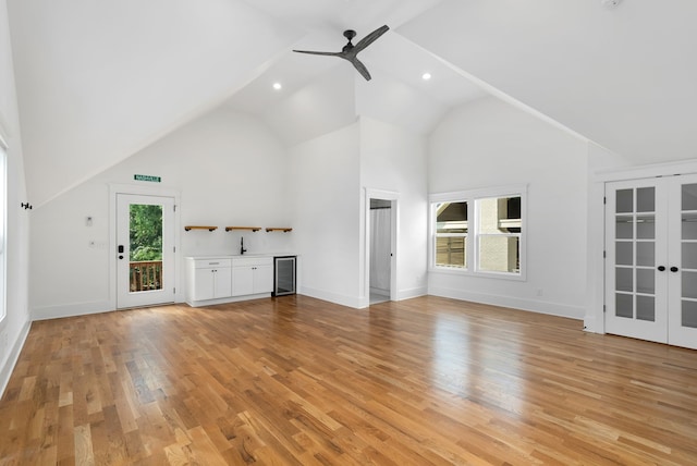 unfurnished living room with a wealth of natural light, ceiling fan, light hardwood / wood-style floors, and vaulted ceiling