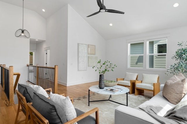 living room featuring high vaulted ceiling, a healthy amount of sunlight, ceiling fan with notable chandelier, and light wood-type flooring