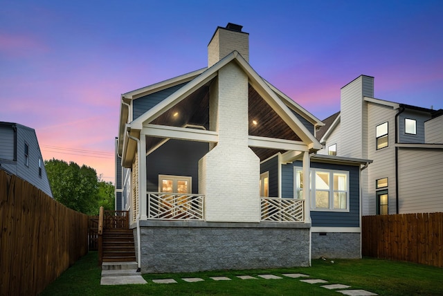 back house at dusk with a lawn