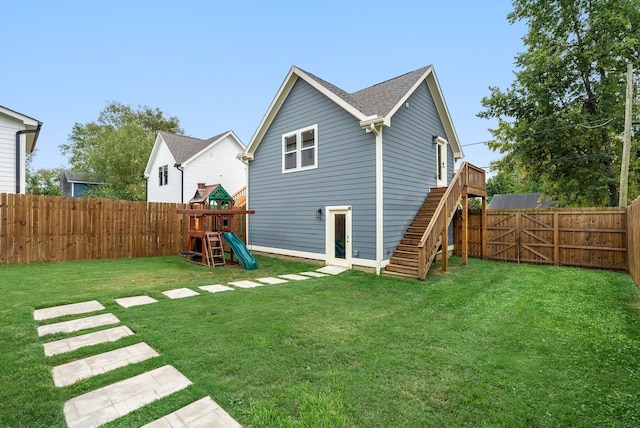 rear view of house with a lawn and a playground