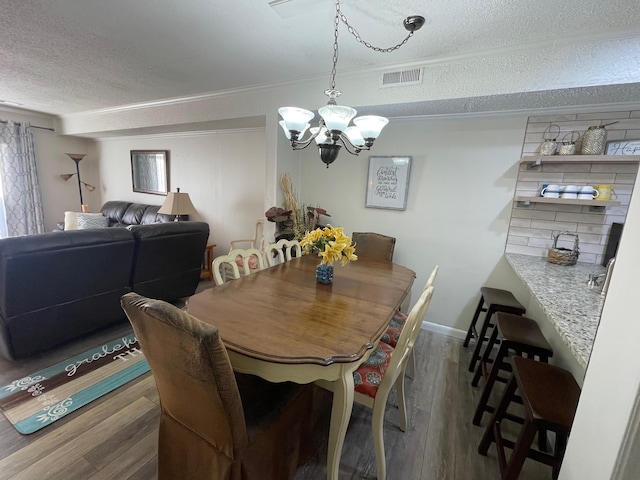 dining space with hardwood / wood-style floors, a textured ceiling, and a notable chandelier