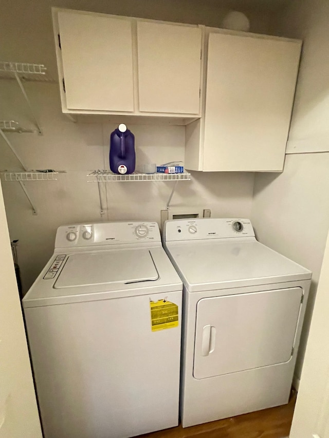 washroom with washing machine and dryer, cabinets, and wood-type flooring