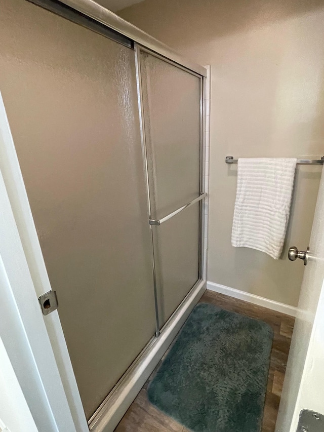 bathroom with an enclosed shower and wood-type flooring