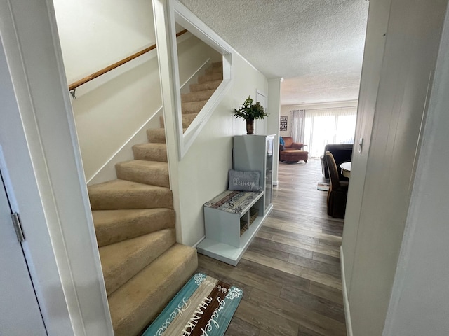 stairs with wood-type flooring and a textured ceiling