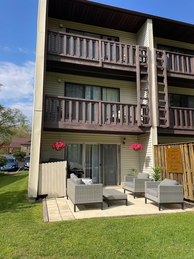 rear view of property featuring a yard, a balcony, and a patio